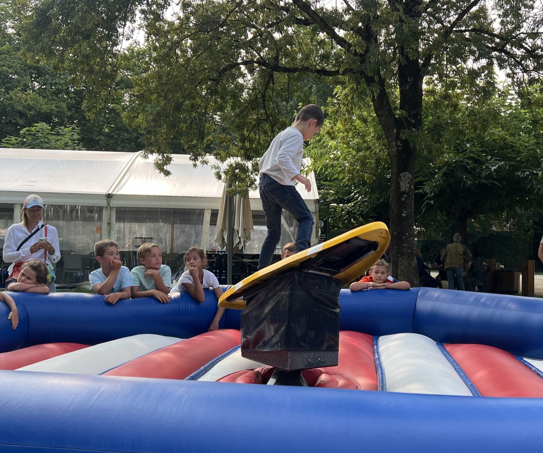 Le surf rotatif Un enfant debout sur un surf entouré d'une structure gonblable pour la réception