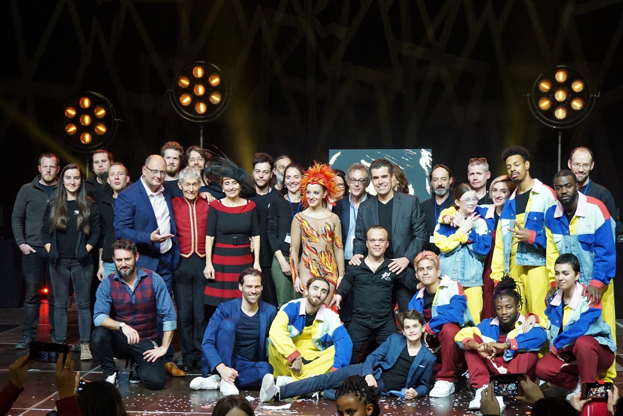 Plateau artistique 2019 Groupe d'artistes sur scène, souriant et vêtus de costumes colorés.