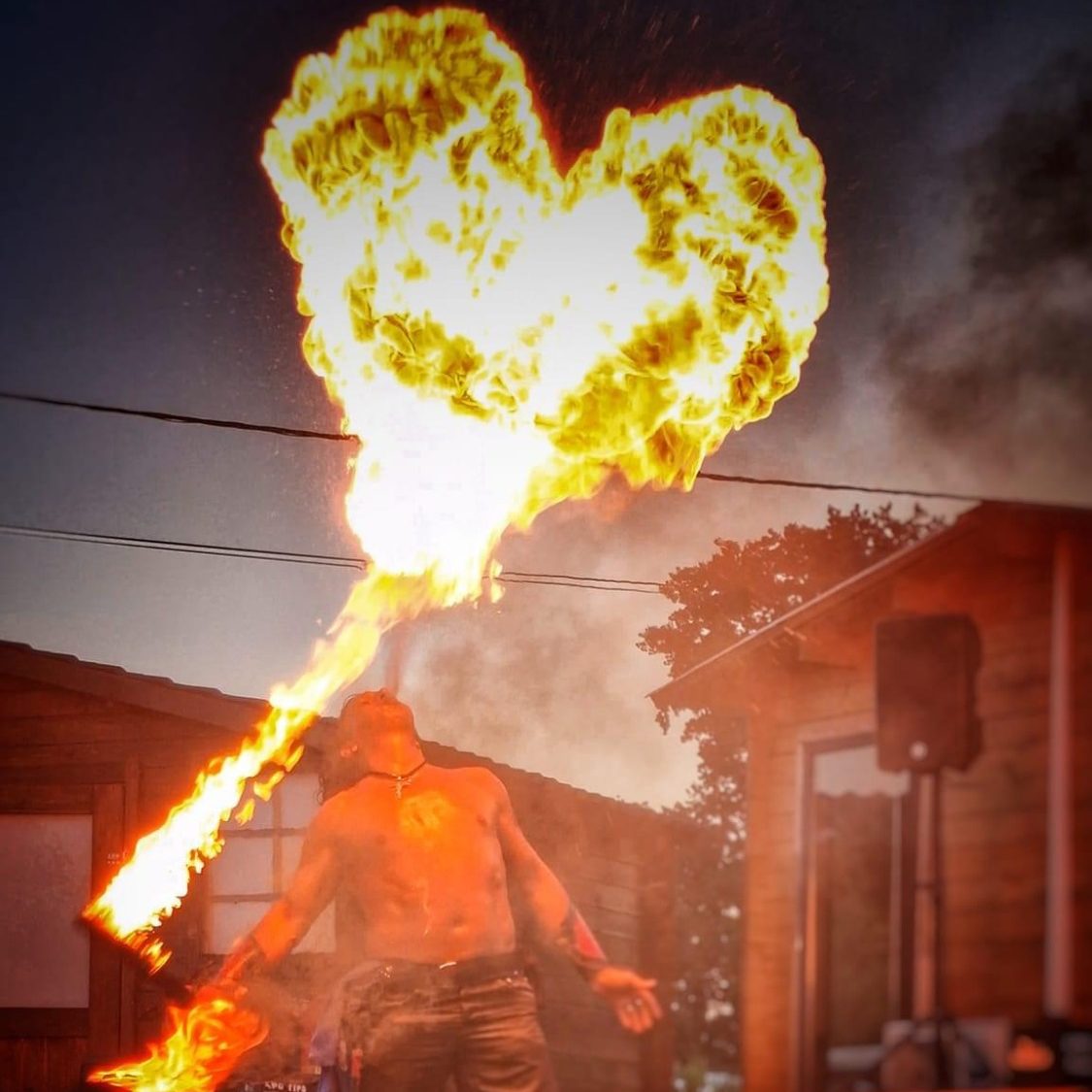 Cracheur de feu Un artiste cracheur de feu forme un cœur avec le feu, sur fond de ciel crépusculaire.