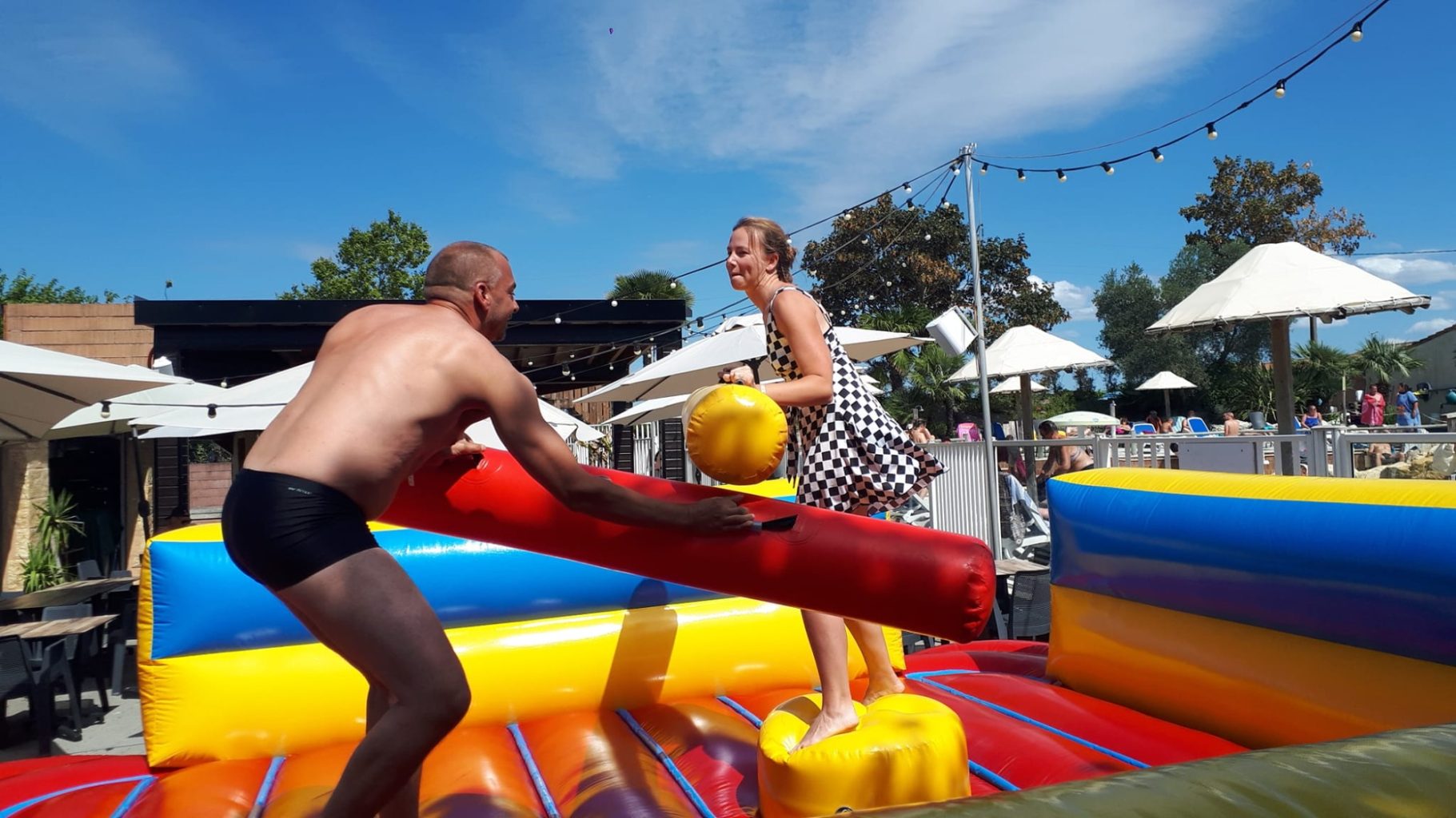 Combat de coton tige Deux personnes jouent sur un jeu gonflable, se battant avec des bâtons colorés.