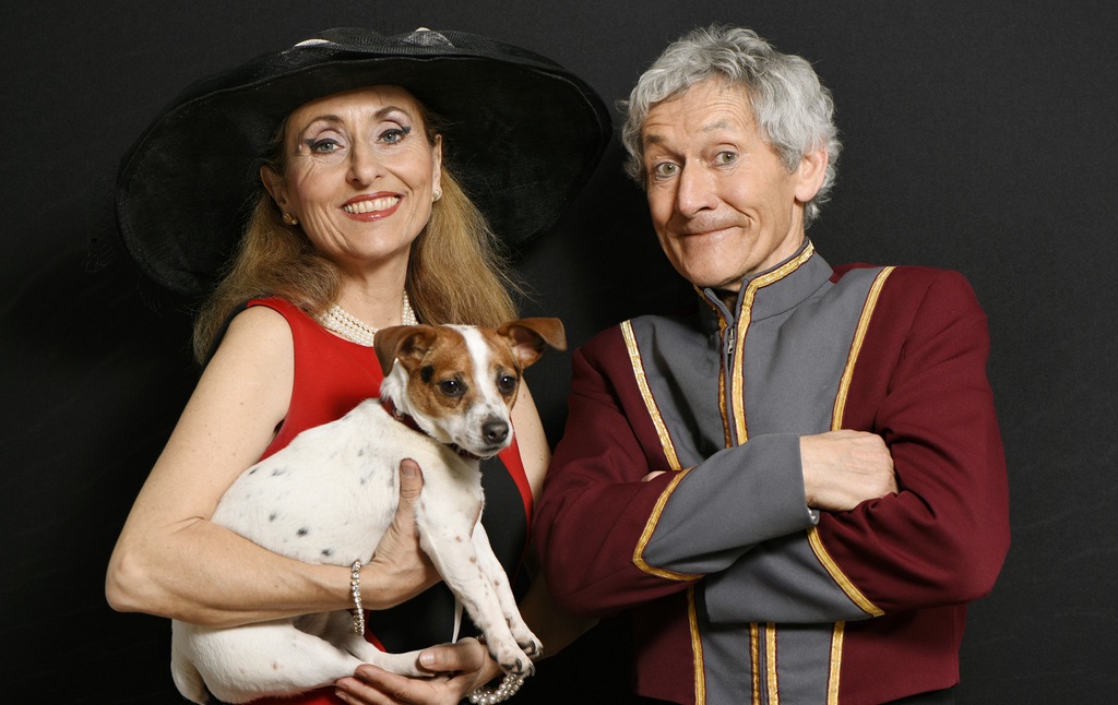 Les Sangers Une femme en rouge avec un chien et un homme en costume souriant.