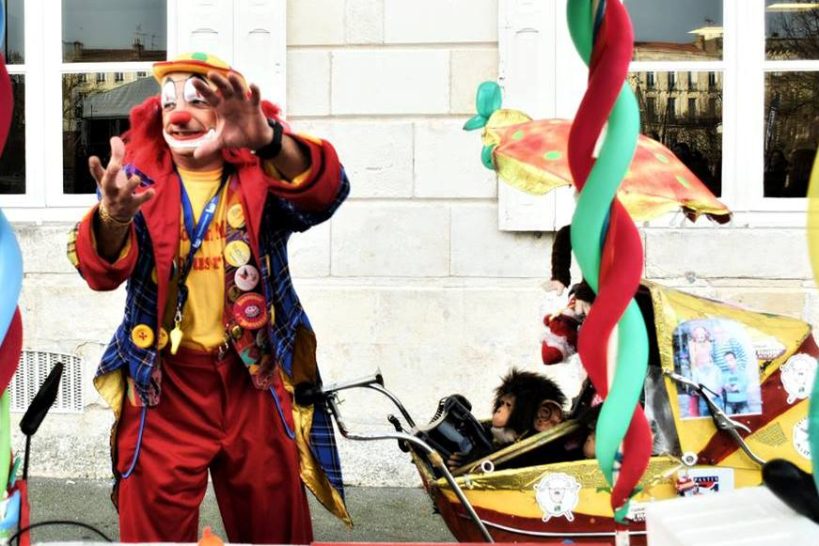 Le clown Melo Un clown coloré avec des accessoires festifs interagit avec le public.