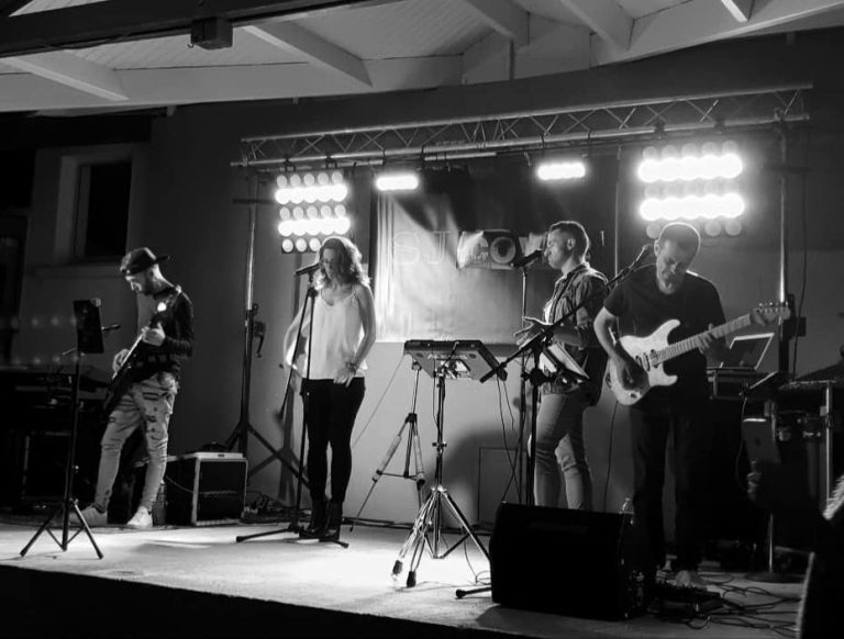 Groupe de musique live sur scène pour un événement d'entreprise Quatuor de musiciens sur scène, avec des instruments et des lumières vives.